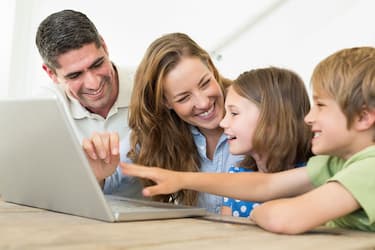 padres felices con sus hijos frente a un notebook