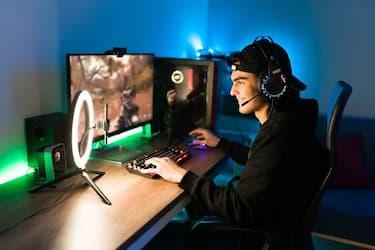 joven feliz sentado frente al escritorio jugando en su pc gamer