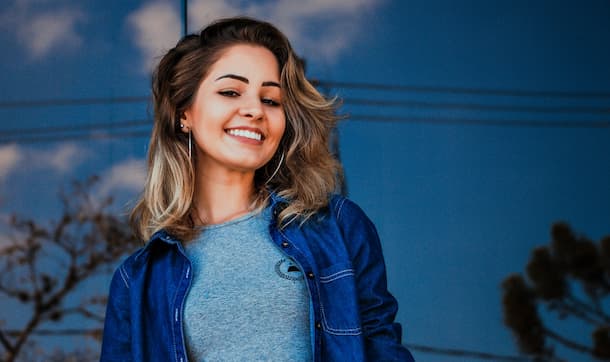 mujer joven sonriendo, mirando hacia la camara en la calle