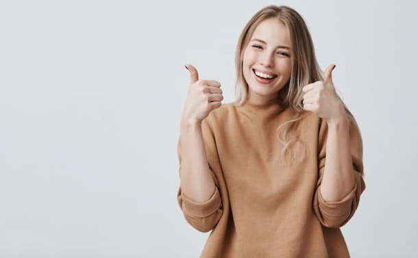 mujer joven sonriendo y haciendo el gesto de me gusta con ambas manos